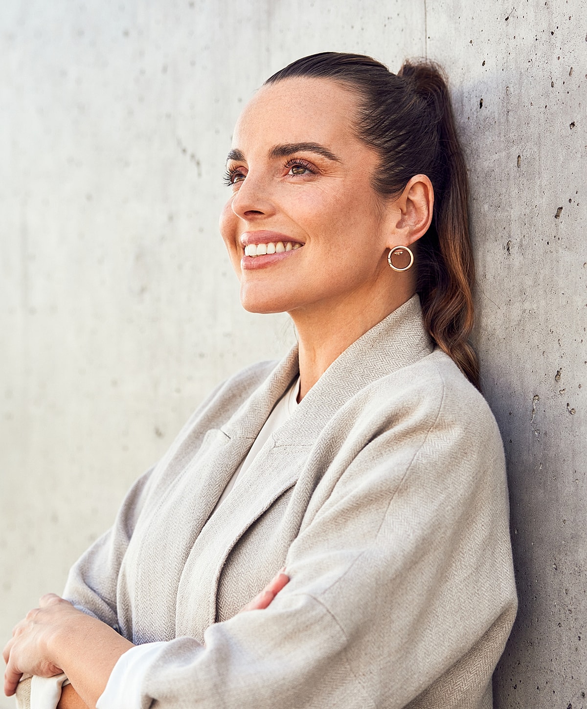 Smiling woman leaning against a concrete wall.