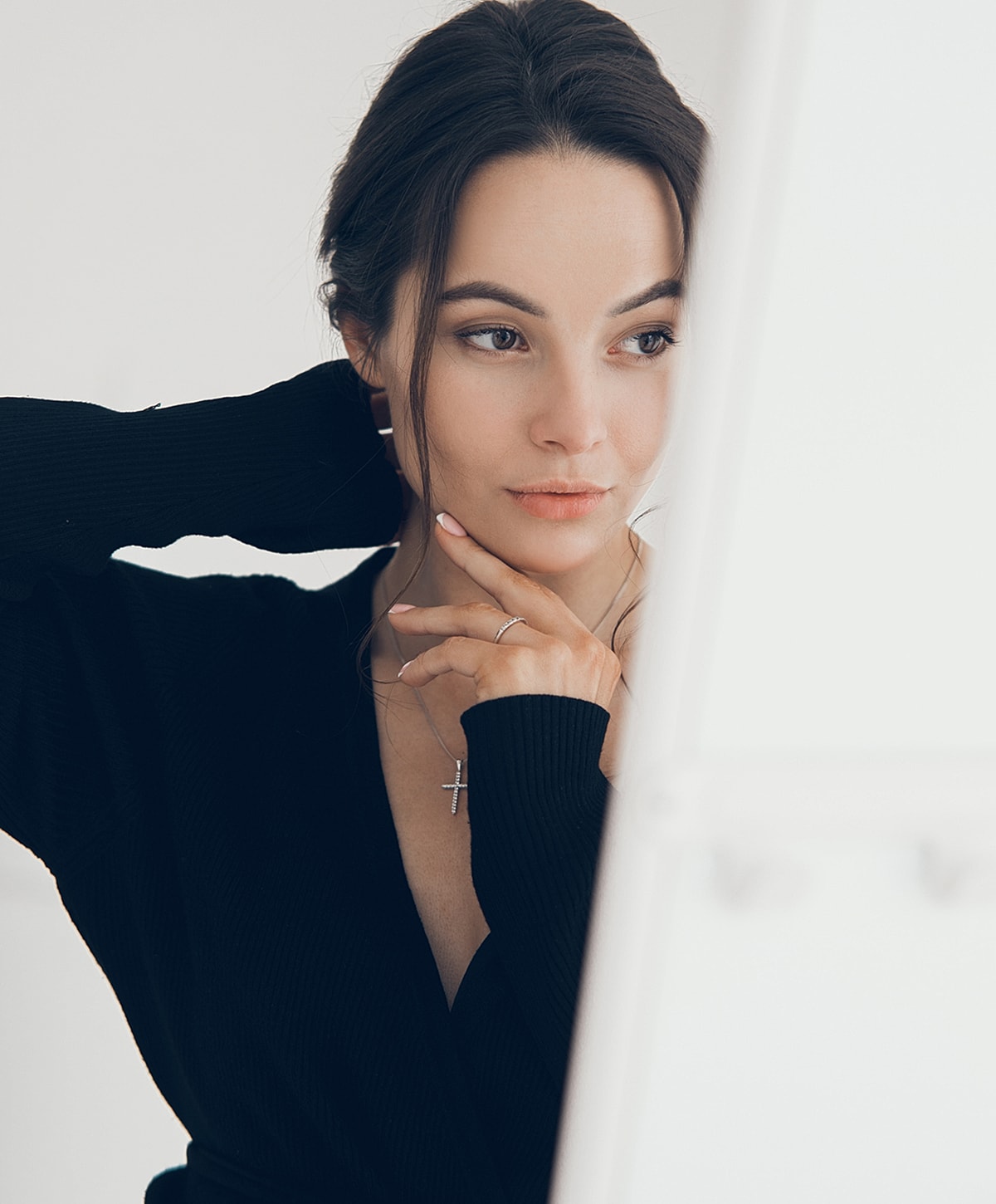Thoughtful woman with elegant jewelry in black outfit.