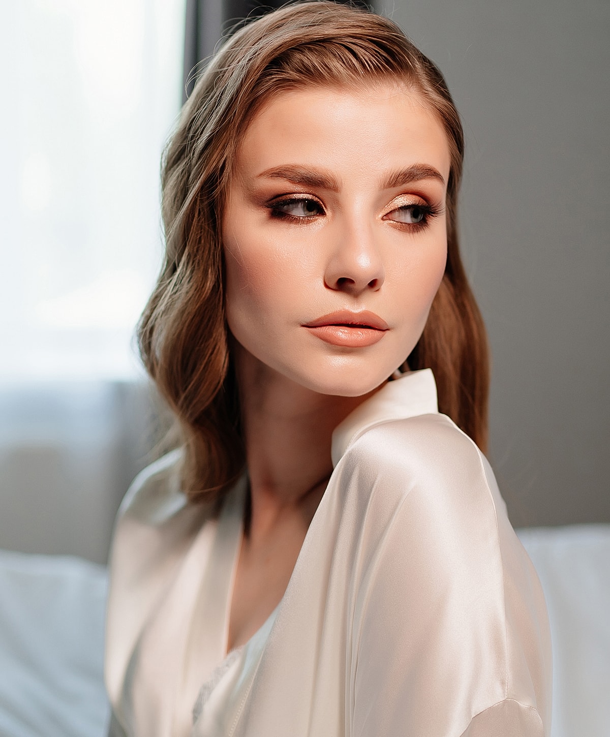 Woman in elegant attire with soft makeup.