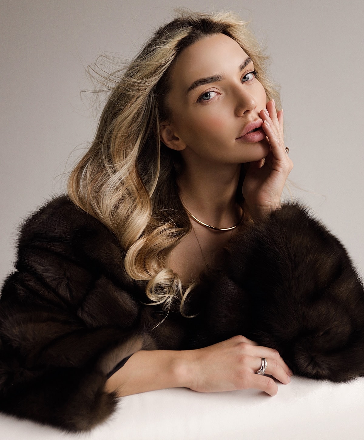 Woman in fur coat with elegant makeup and jewelry.