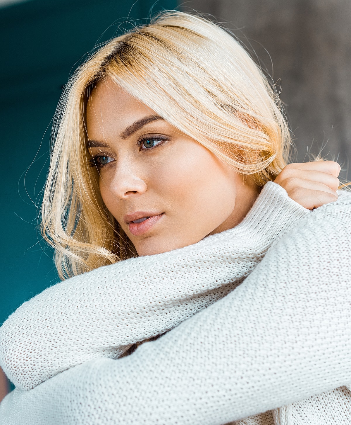 Woman wearing a cozy sweater, thoughtful expression.