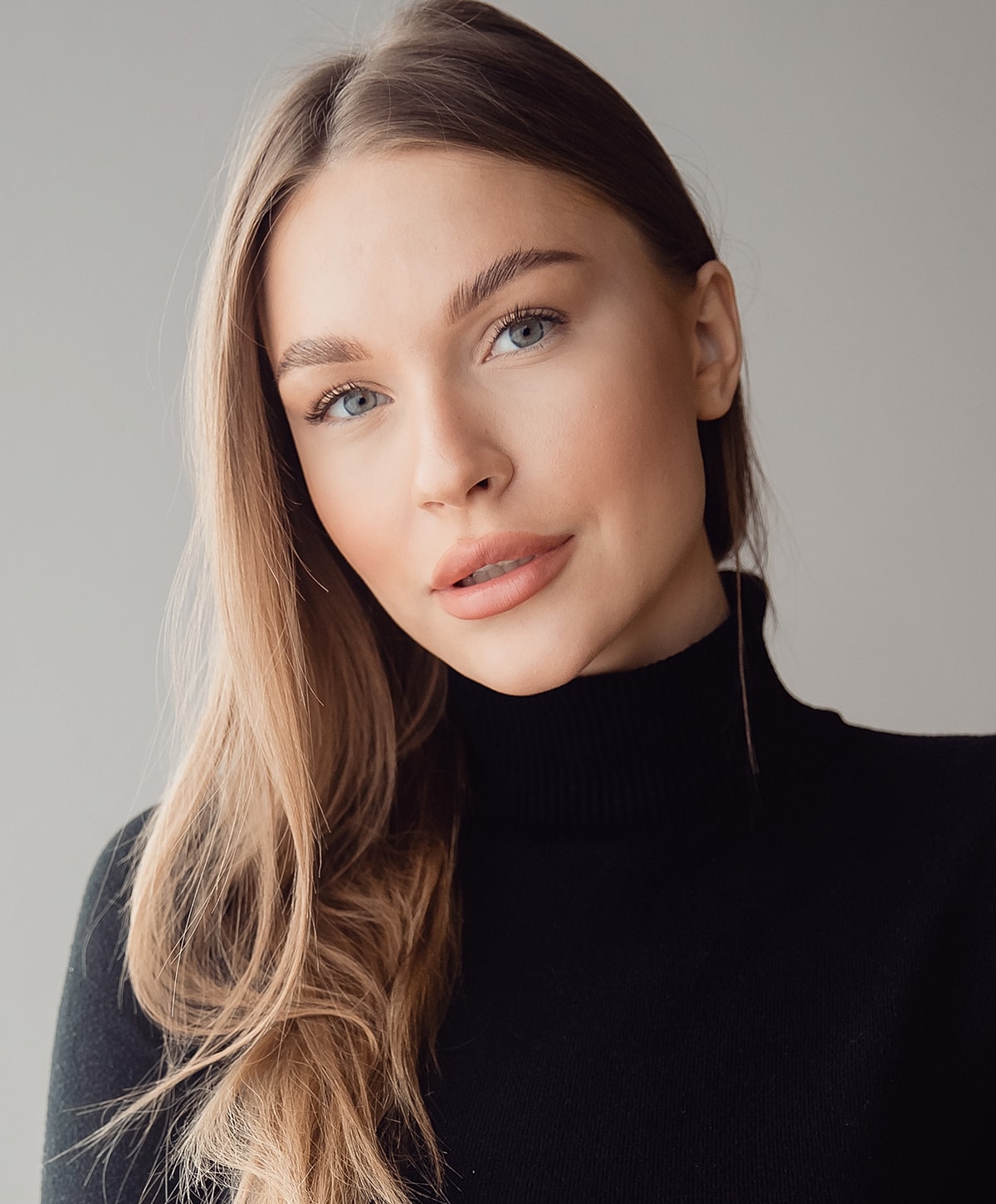 Smiling woman with long hair in black sweater.
