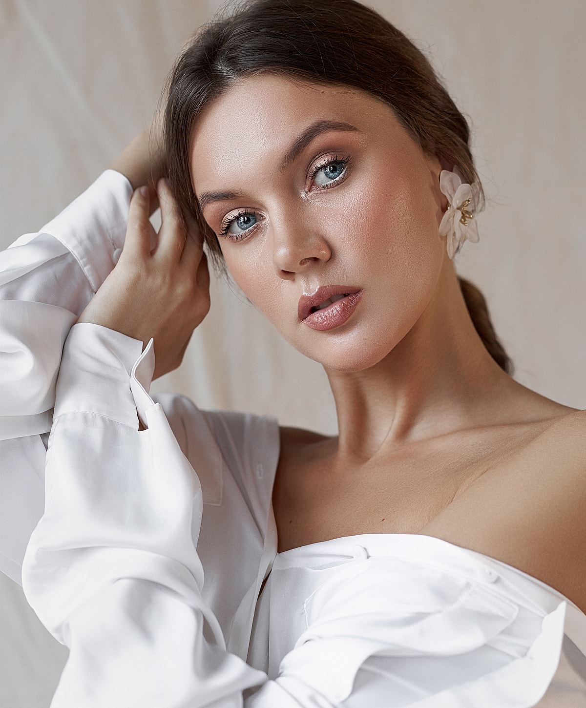 Model in white blouse with flower accessory.