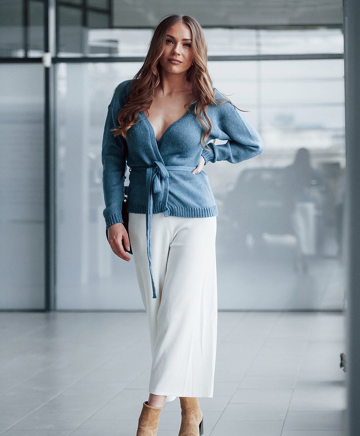Woman in stylish blue sweater and white pants.