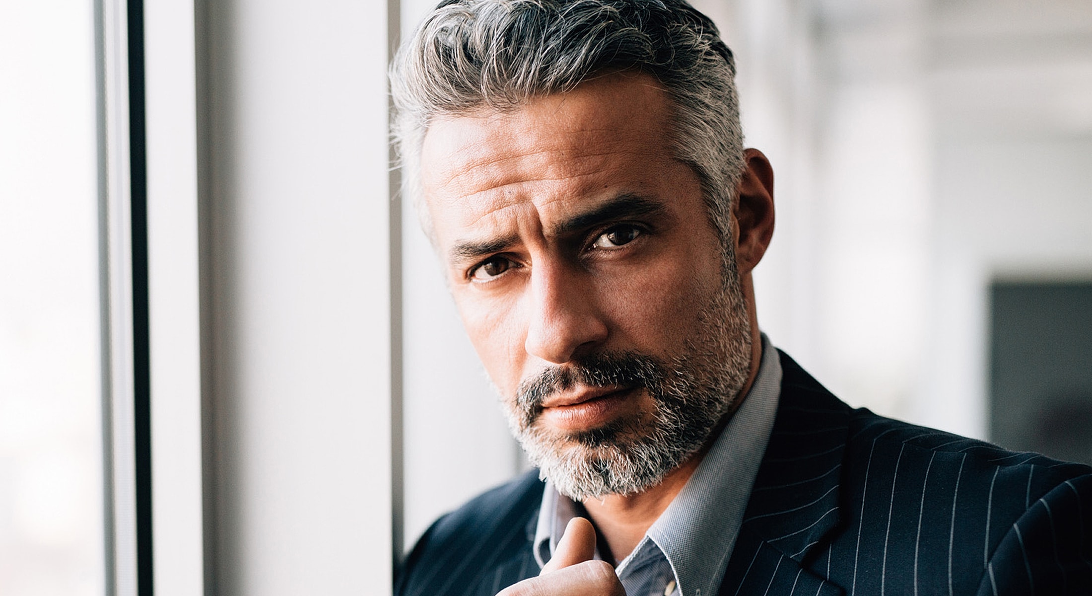 Man with gray hair and beard, serious expression.