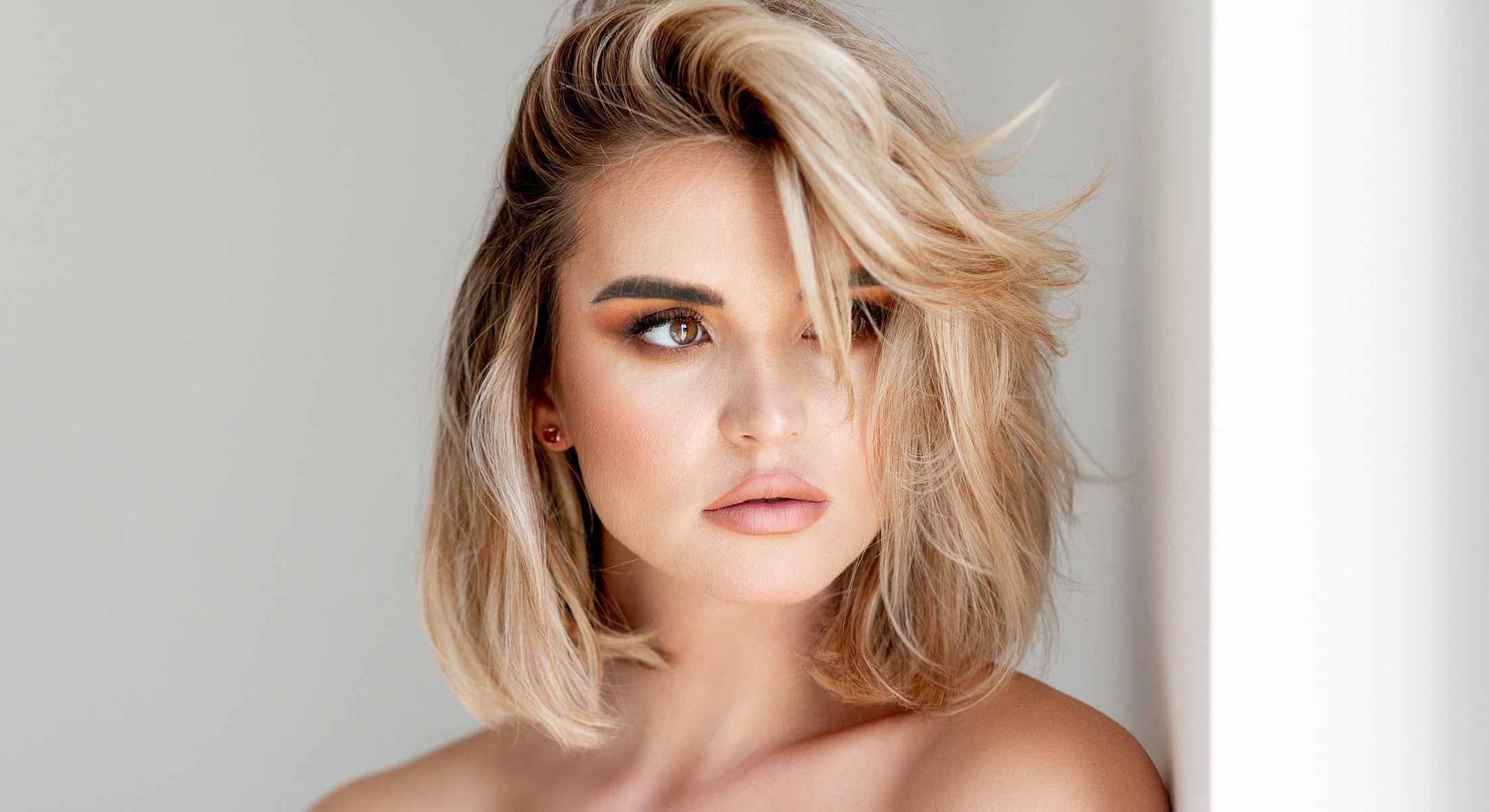 Woman with stylish blonde hair and natural makeup.
