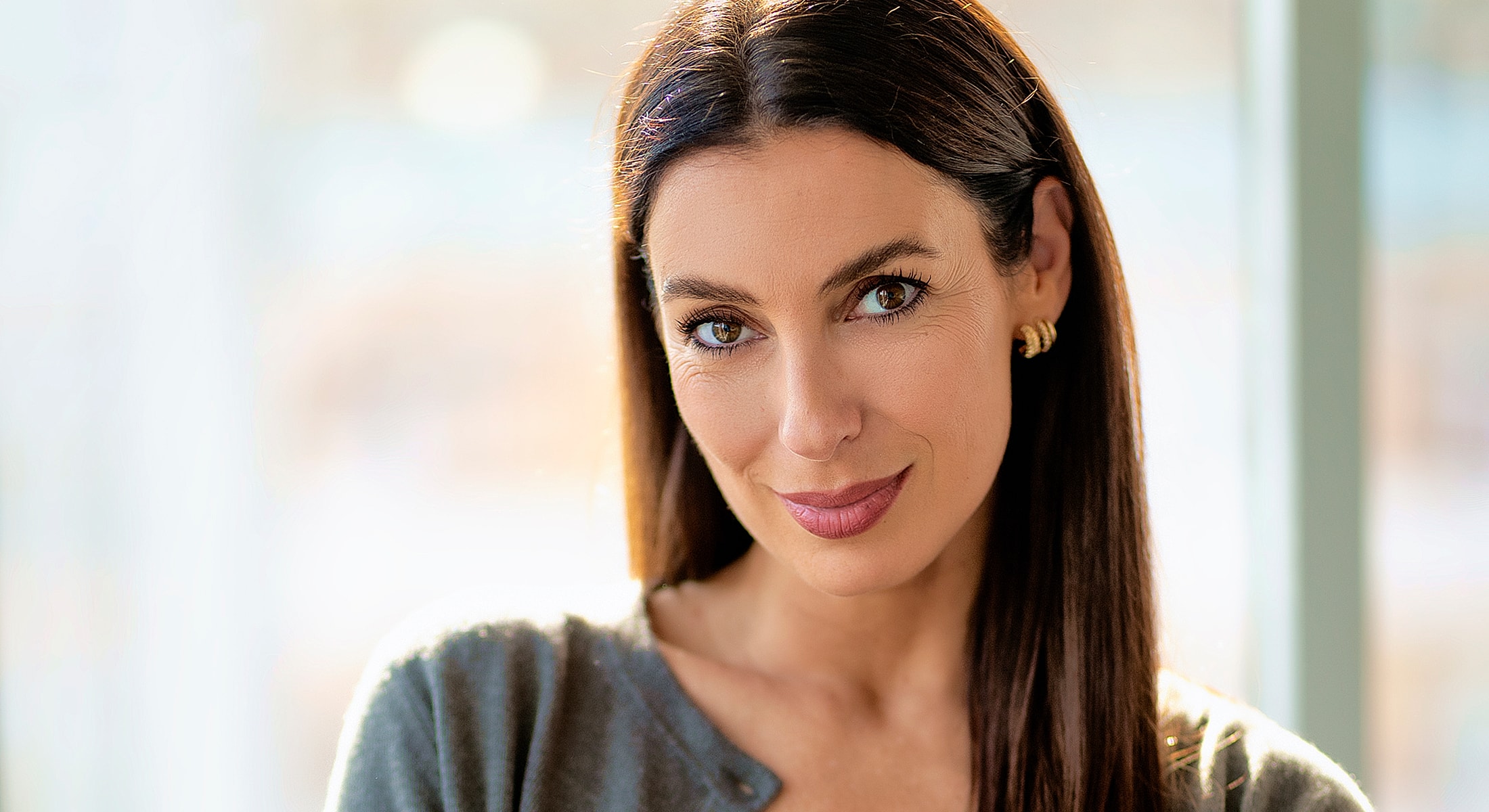 Smiling woman with long dark hair indoors.
